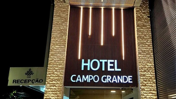 Esterno dell'Hotel Campo Grande di sera, con un design moderno caratterizzato da strisce verticali illuminate e un'area reception.