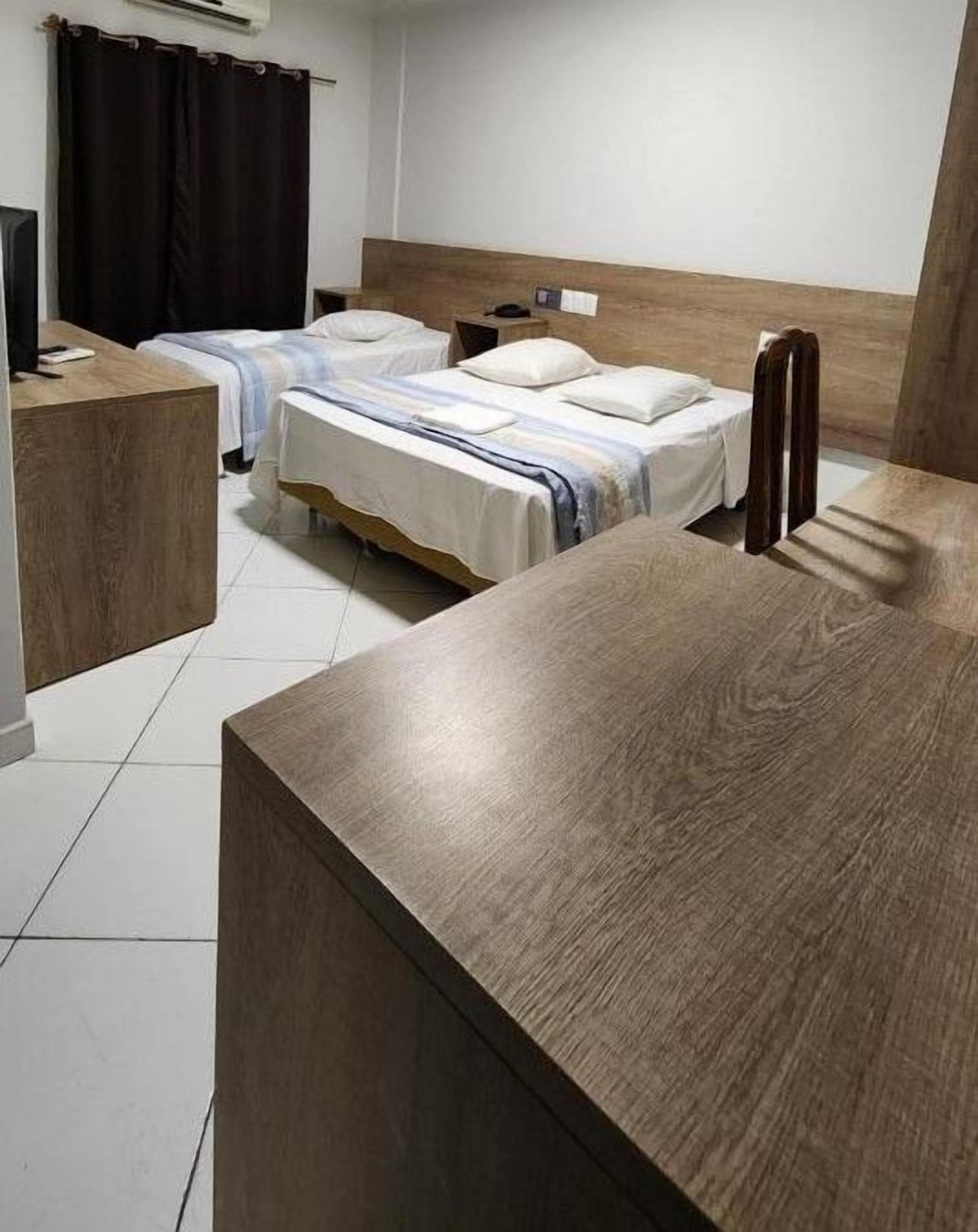 A hotel room with two beds, a wooden headboard, a desk, and a chair.