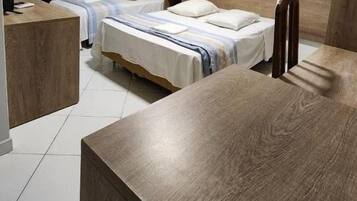 A hotel room with two beds, a wooden headboard, a desk, and a chair.