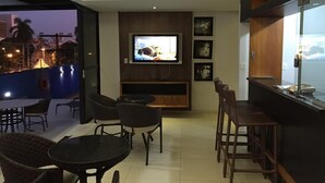 Un soggiorno moderno con una TV a schermo piatto, posti a sedere comodi e vista sulla città.