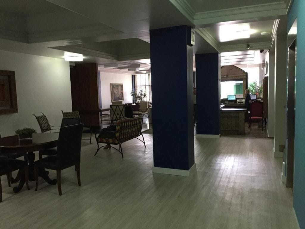 A spacious room with a dining area, a reception desk, and a large window.