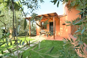 A patio area with a pergola, outdoor seating, and a door leading to the interior.