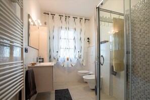 A modern bathroom with a shower, toilet, and sink.