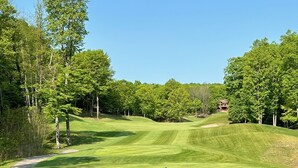 Un parcours de golf avec un gazon bien entretenu, des bunkers de sable et un bâtiment situé au loin.