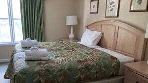 A neatly made bed with a floral bedspread, a bedside lamp, and a nightstand with a lamp. - Desired Resort on Hilton Head Island (3 BD, 3BA Condo near beach) (Hilton Head)