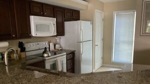 A kitchen with granite countertops, a white refrigerator, a microwave, a stove, and a sink. - Desired Resort on Hilton Head Island (3 BD, 3BA Condo near beach) (Hilton Head)