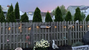 A wooden fence with a 'GARDEN' sign, decorative birdhouse, and a white rabbit statue.