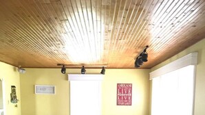 A living room with a wooden ceiling, a sofa set, a small table, and a wall with a motivational quote.