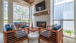 A cozy outdoor seating area with wooden furniture and a fireplace. - Southern Sand: beach house with beautiful forest views (Santa Rosa Beach)