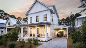 A two-story white house with a porch, a garage, and a driveway. - Southern Sand: beach house with beautiful forest views (Santa Rosa Beach)