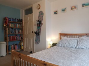 Une chambre à coucher avec un lit, une bibliothèque, une porte et un mur orné de tableaux.