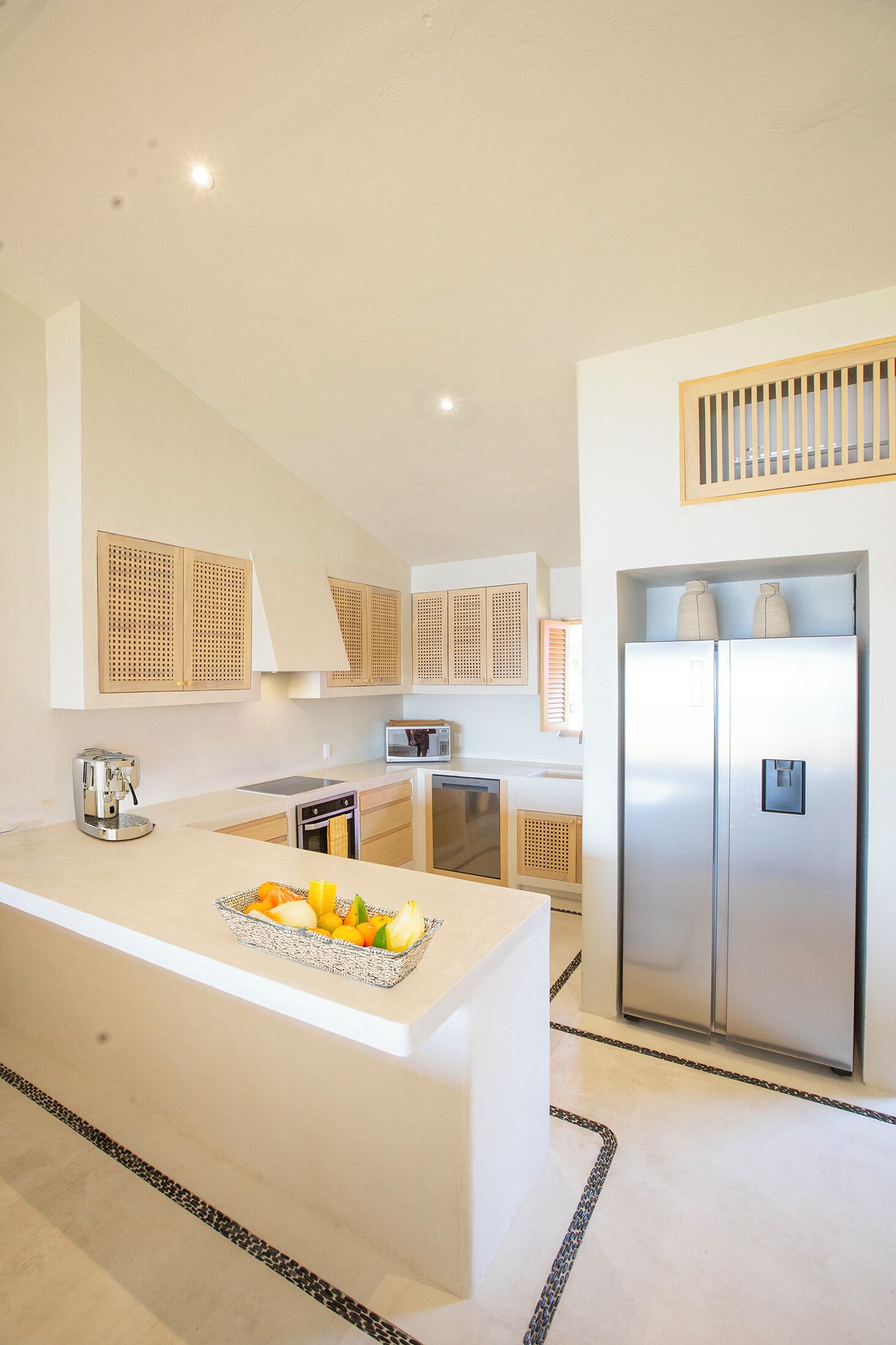 Una cocina moderna con una isla central, electrodomésticos de acero inoxidable y un horno empotrado.
