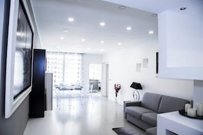 A modern living room with a grey sofa, a coffee table, and a TV on a stand.