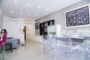 A modern kitchen with a dining area, clear chairs, and a cityscape artwork on the wall.