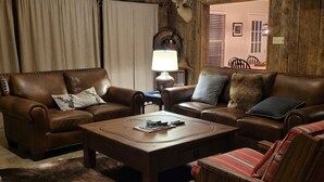A cozy living room with leather sofas, a coffee table, and a fur rug. - Shadow Dance Ranch-Private 2000 Acres and 2 Lakes with Plenty of Water to Enjoy! (Tarpley)