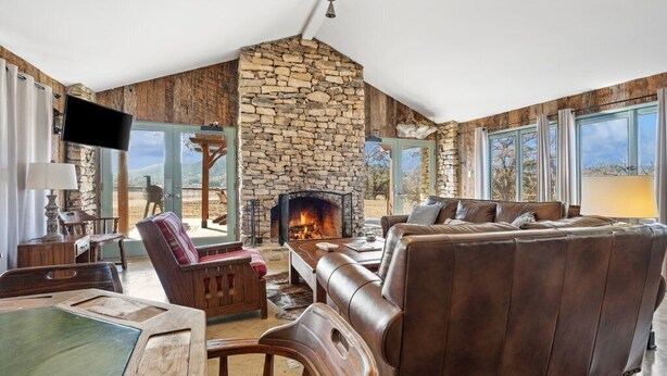 Una sala de estar acogedora con chimenea de piedra, sofá de cuero y muebles de madera.