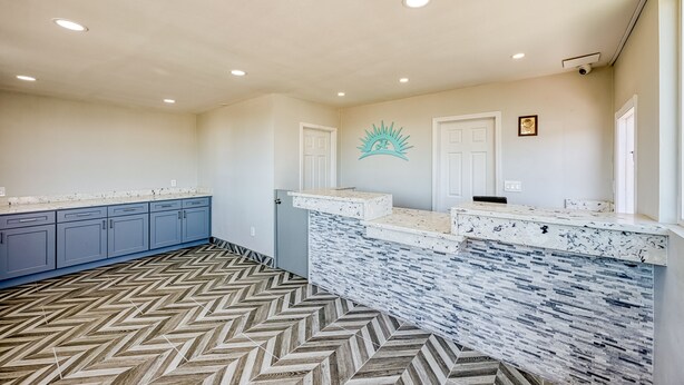 A modern kitchen with a herringbone-patterned floor, a marble countertop, and a decorative wall piece. - ERTH INN by AGA - Mojave (Mojave)