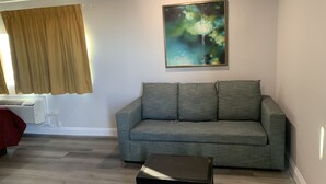 A living room with a grey sofa, a small black coffee table, and a painting on the wall. - ERTH INN by AGA - Mojave (Mojave)