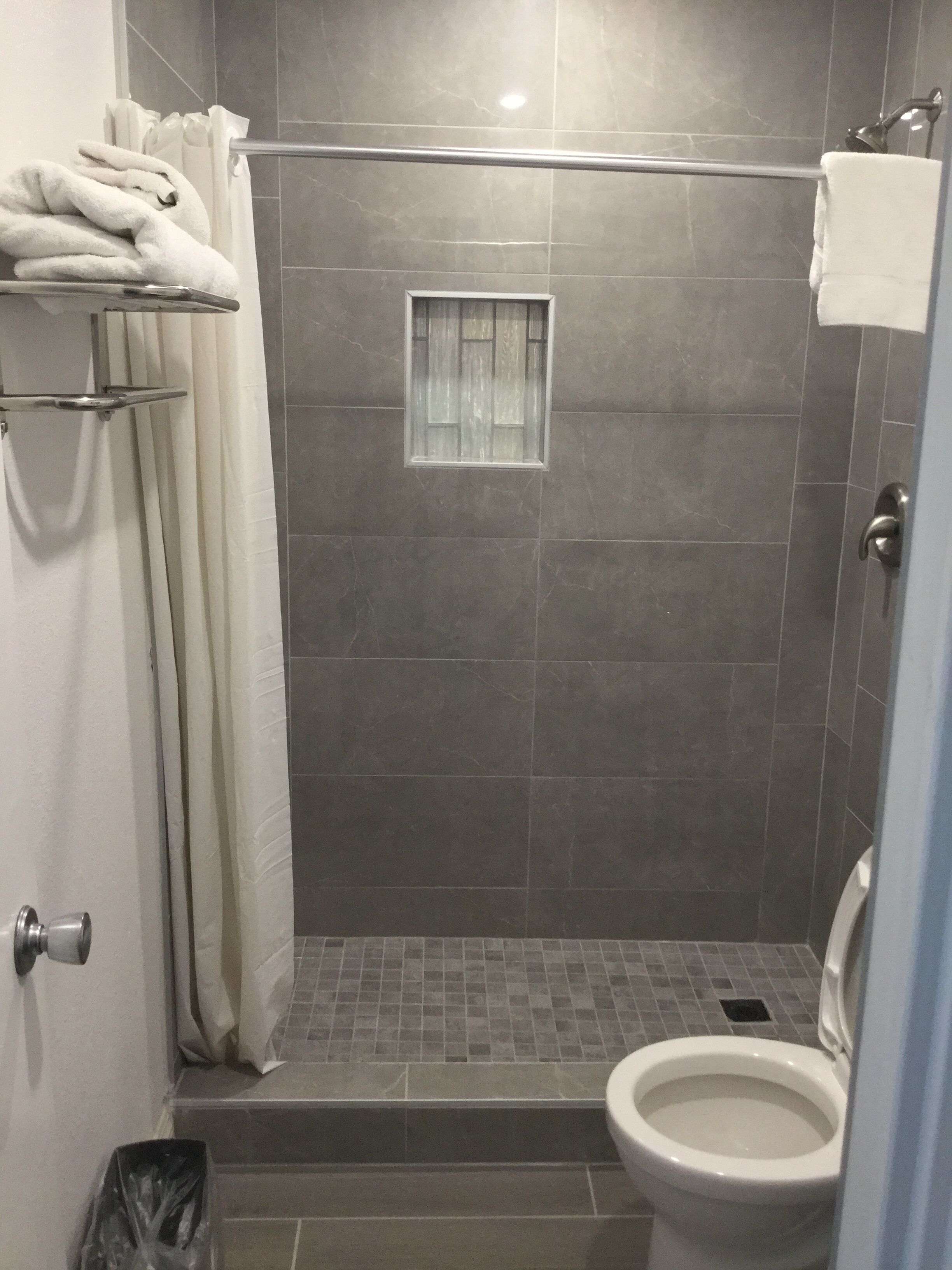 Een douchegedeelte met een glazen deur, een klein raam en een toilet.