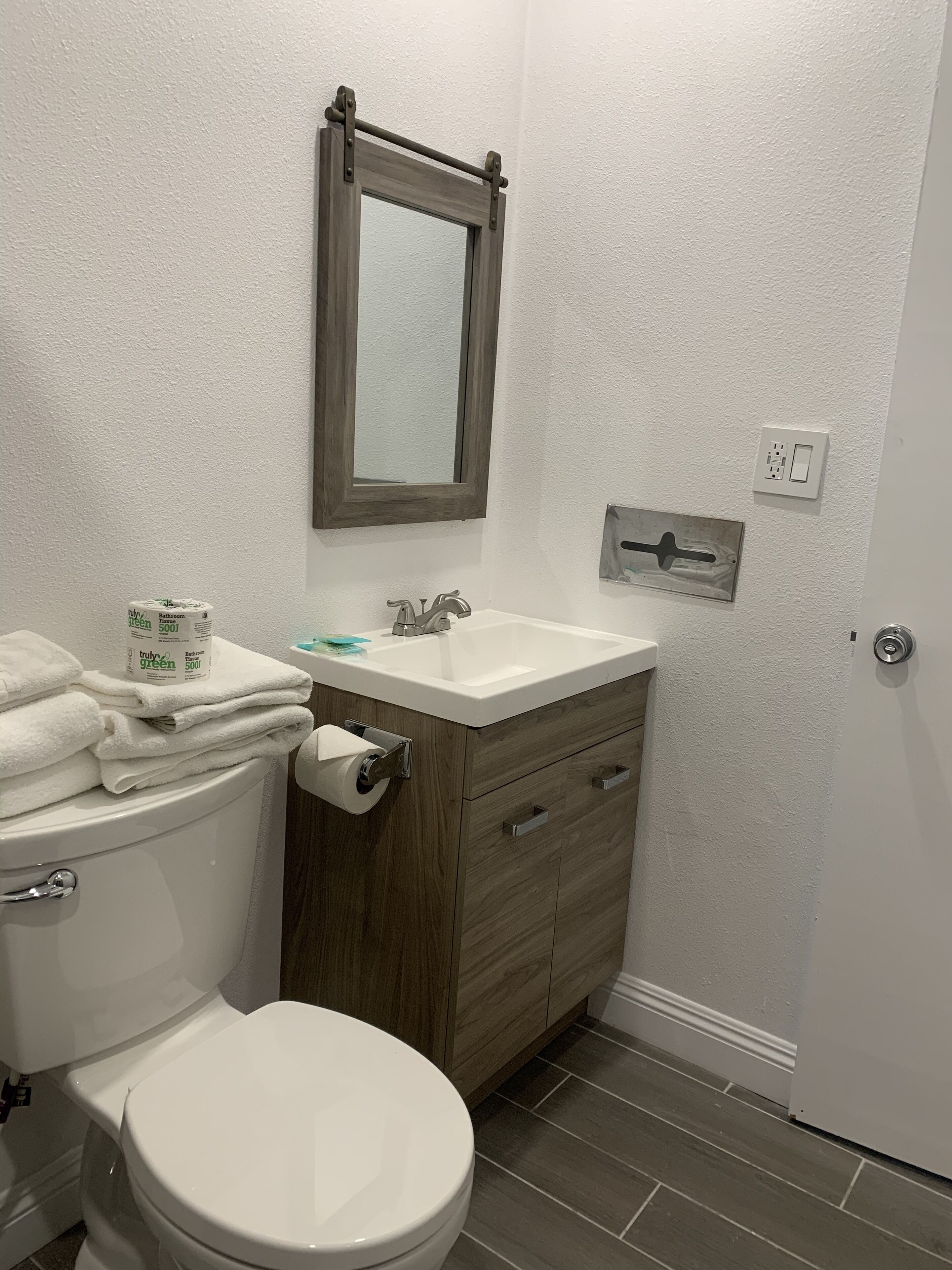 A bathroom with a toilet, sink, and mirror.