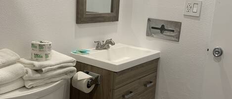 A bathroom with a toilet, sink, and mirror.