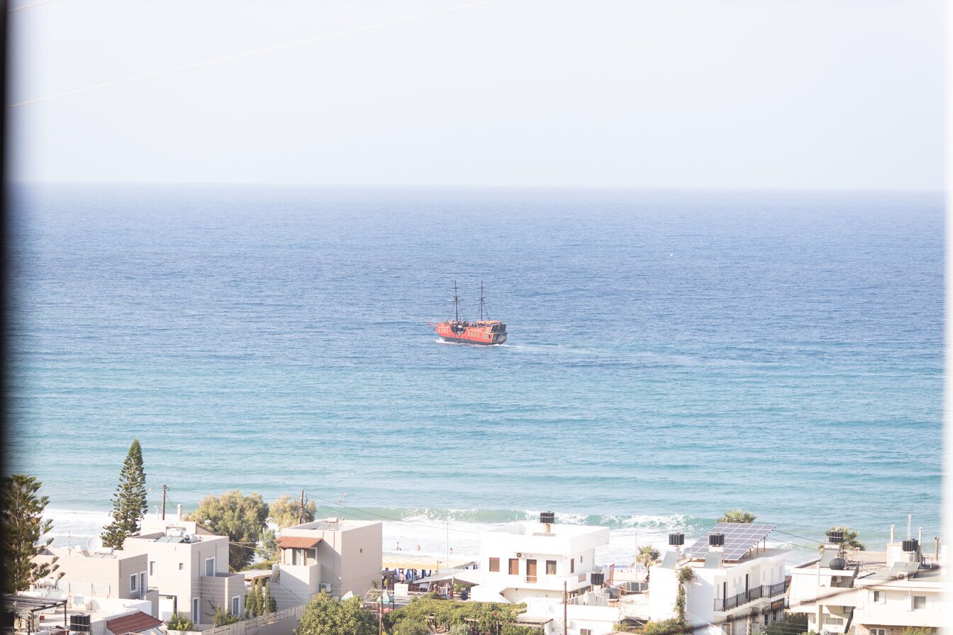 A coastal town with buildings near the sea, a boat in the water, and a clear sky.