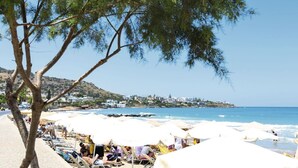 Een strand met parasols en mensen die zonnebaden.