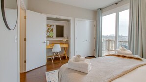 Un dormitorio con una cama grande, un escritorio, una silla, un ventanal con vistas y un ventilador de techo.