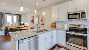 Una cocina moderna con armarios blancos, electrodomésticos de acero inoxidable e iluminación colgante.