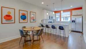 Una cocina moderna con una isla central, taburetes de bar y una mesa de comedor con individuales redondos.
