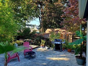 A patio area with a barbecue grill, outdoor seating, and potted plants.