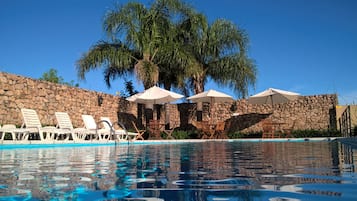 Una piscina al aire libre de temporada, sombrillas