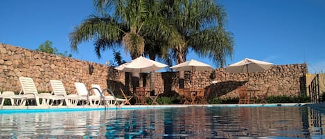 Una piscina al aire libre de temporada, sombrillas