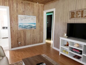 Ein Wohnzimmer mit Holzwänden, einem Gemälde, einem Fernseher und einem Bücherregal.