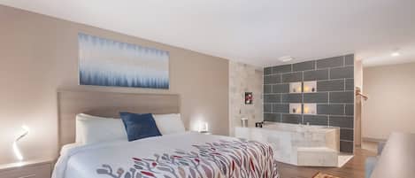 Ein modernes Hotelzimmer mit einem großen Bett, einem Badezimmer mit einer Badewanne und einer Dekowand.