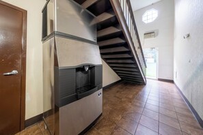 A hallway with a stainless steel appliance, a wooden door, and a staircase with a view to the outside. - Red Roof Inn Dahlgren - Naval Base (King George)