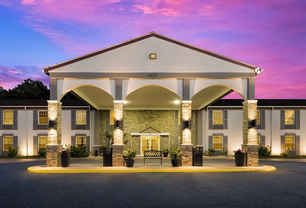 A hotel with a classic architectural design, featuring a central entrance with a covered walkway, stone pillars, and a numbered address sign.