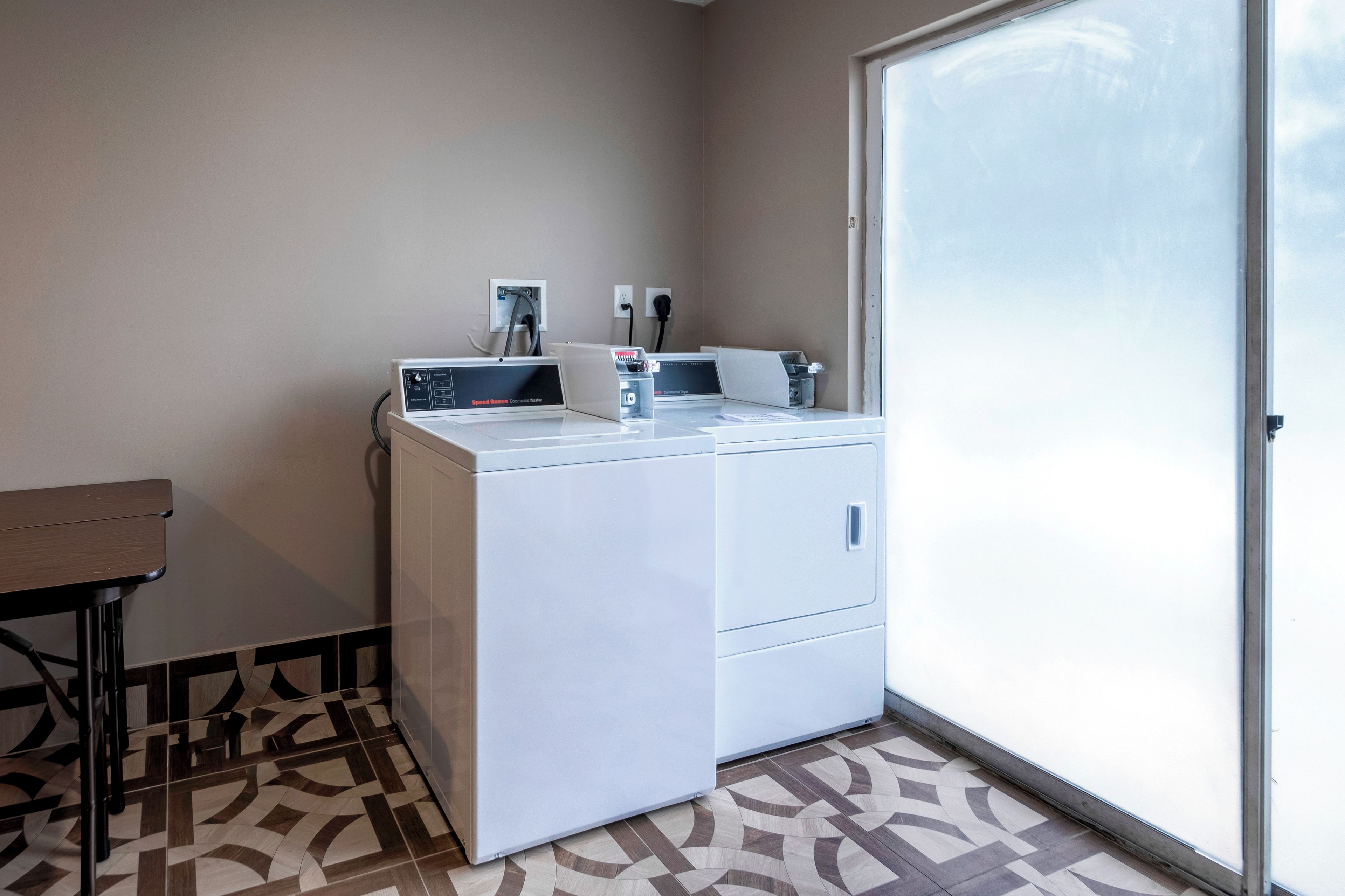 Un espace buanderie compact comprenant un lave-linge, un sèche-linge et une petite table.