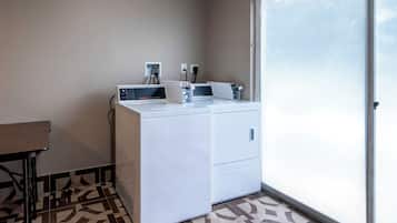 Un espace buanderie compact comprenant un lave-linge, un sèche-linge et une petite table.