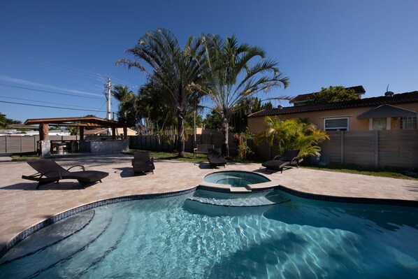 A swimming pool with a curved design, surrounded by lounge chairs and palm trees.