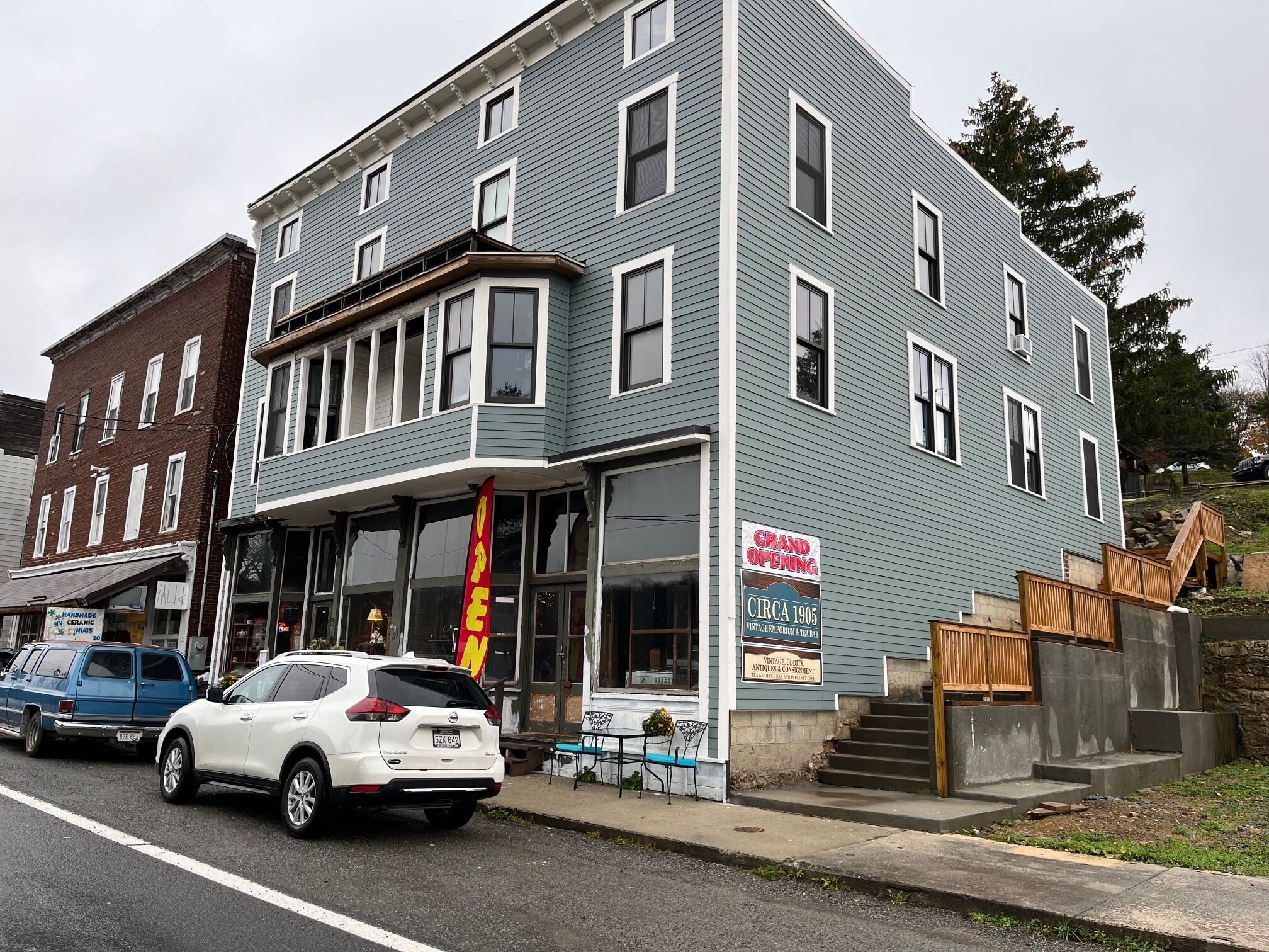 A two-story building with a vintage shop on the ground floor, a grand opening sign, and a staircase leading to the upper level.