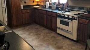 Una cocina con armarios de madera, estufa, microondas y refrigerador.