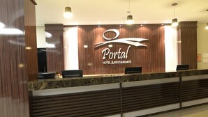 Un mostrador de recepción de hotel con diseño de paneles de madera y el nombre 'Portal Hotel & Restaurante' exhibido con gran destaque.