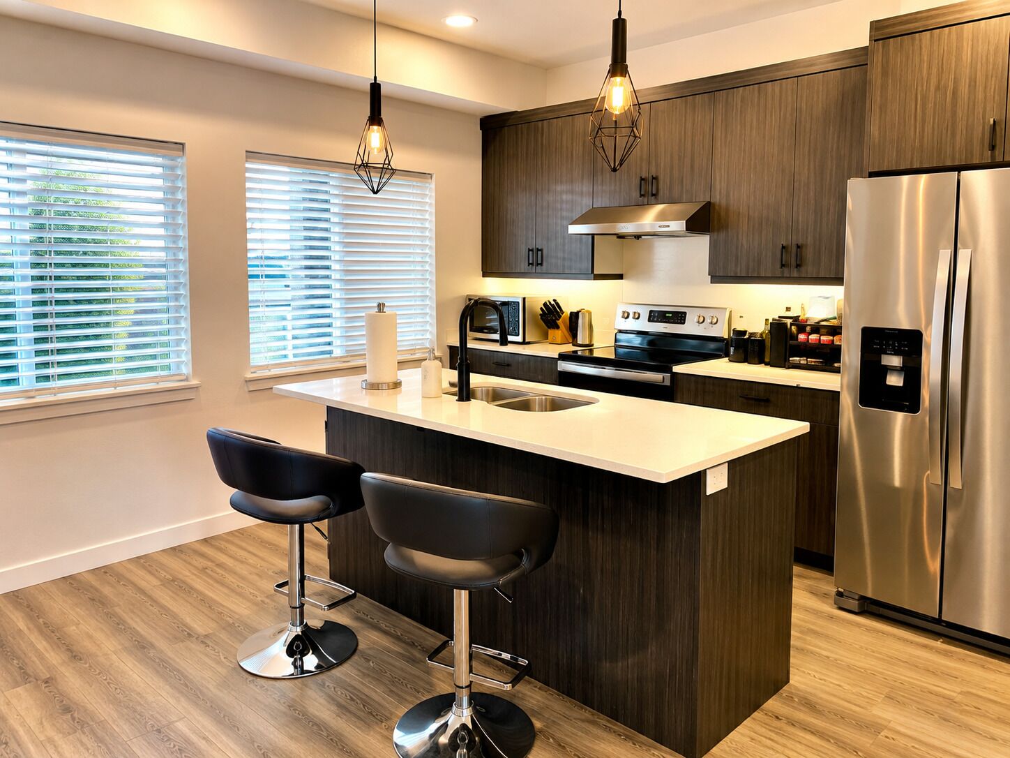 A modern kitchen with a central island, stainless steel appliances, and bar stools.