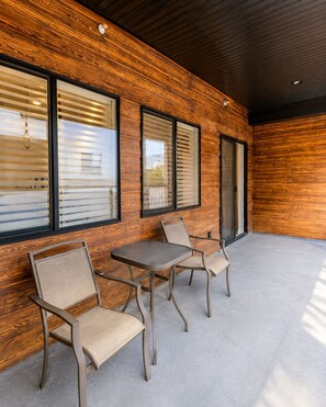 An outdoor seating area with a table and four chairs, wooden panel walls, and large windows with blinds. - Spacious Draper Retreat 3BR, Sleeps 8 - Near Snowbird (Draper)