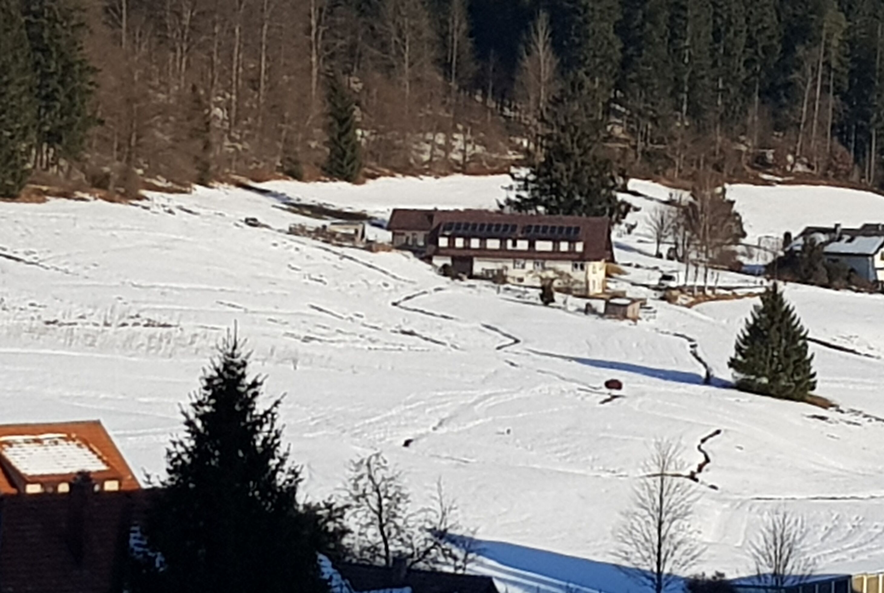 A snow-covered landscape with a building featuring multiple windows and a sloped roof.