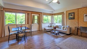 Ein geräumiges Wohnzimmer mit Essbereich, großen Fenstern, einem Deckenventilator und einer wandmontierten Klimaanlage.