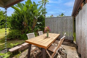 A wooden patio table with chairs, a bench, and a vase of flowers. - A Princeville Suite for all your Needs (Princeville)