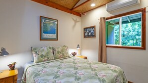 Ein Schlafzimmer mit Bett, Nachttisch, Lampe, einem gerahmten Stadtplan und einem Fenster mit Blick auf Bäume.