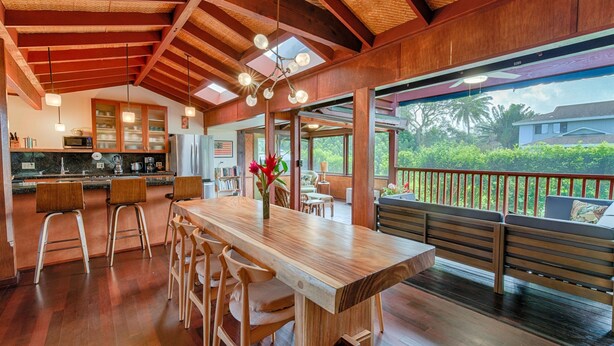 Una cocina amplia con vigas de madera, una isla grande con taburetes de bar y vistas al exterior.